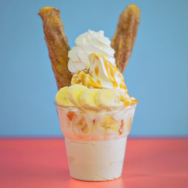 Sundae with vanilla ice cream, caramel sauce, bananas, whipped cream, and churros